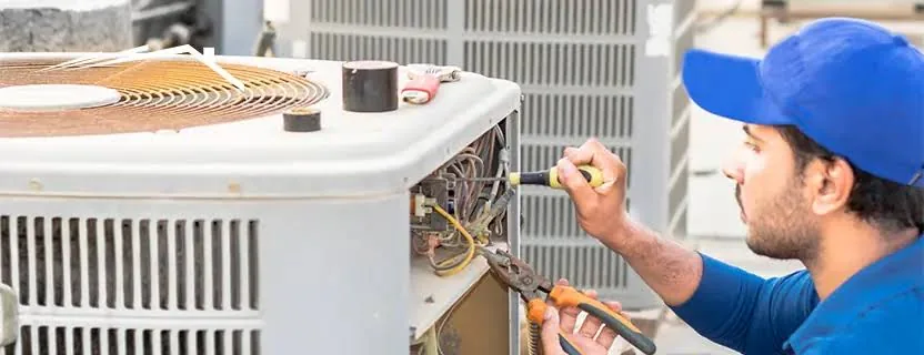 Technician repairing the wiring inside an outdoor AC unit
