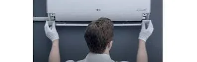 Technician checking the airflow section of a wall-mounted HVAC unit